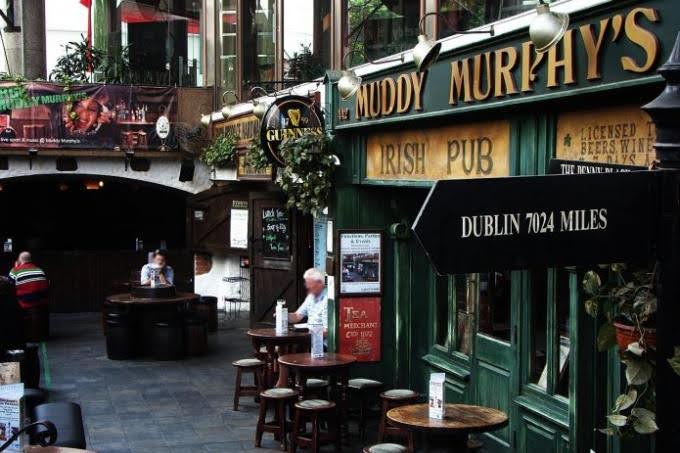An archival photograph of Muddy Murphy’s green Irish pub frontage and barrel tables